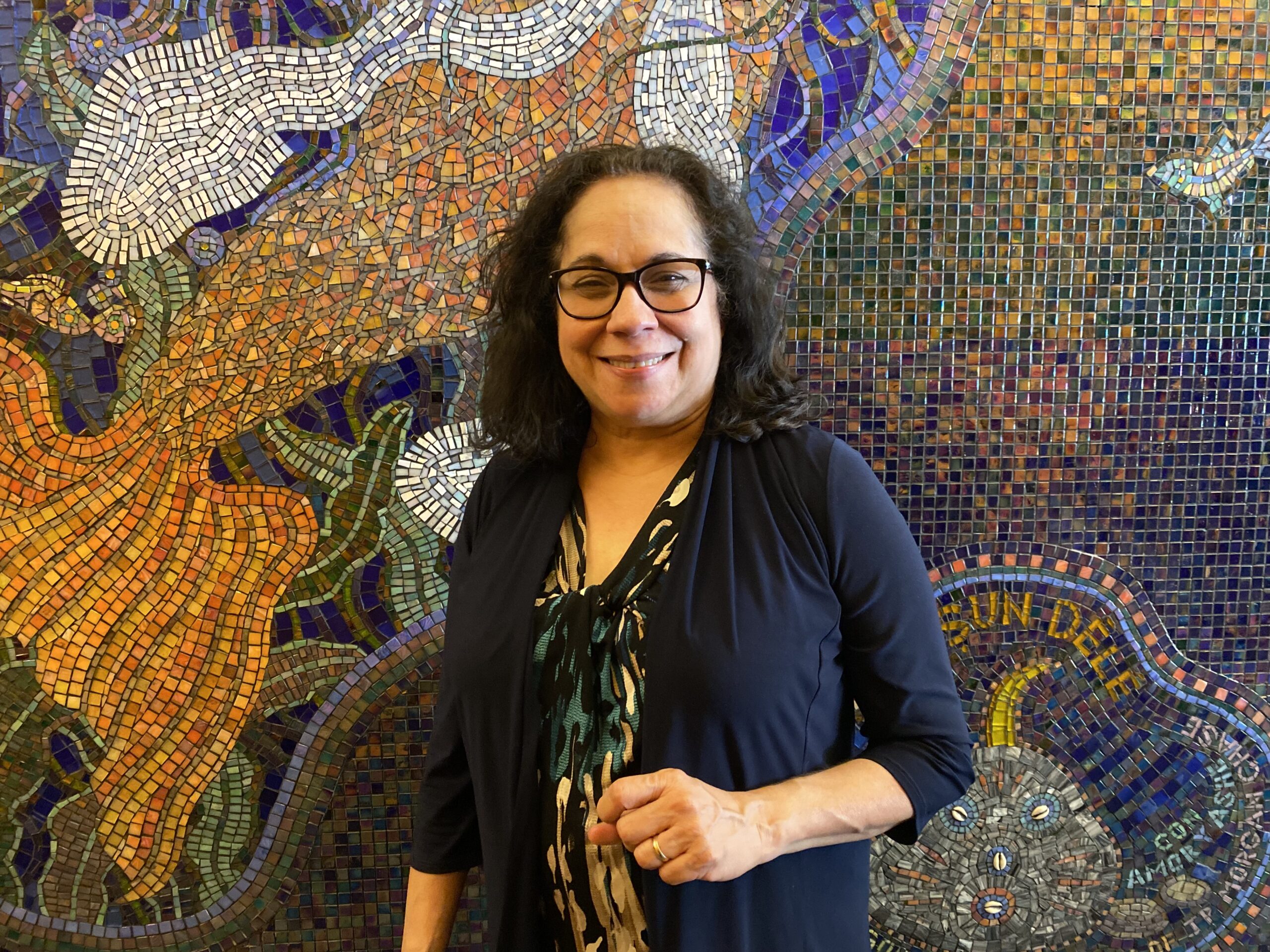 Rosalba Rolón, the creator and director of TORCHED!, posing against a mural at Pregones Theater.